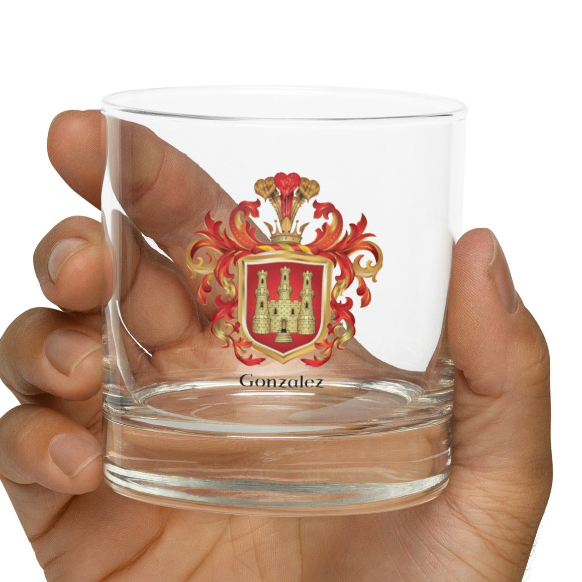 Hand holding a clear glass with a red and Gonzalez-Family-Crests on a white background