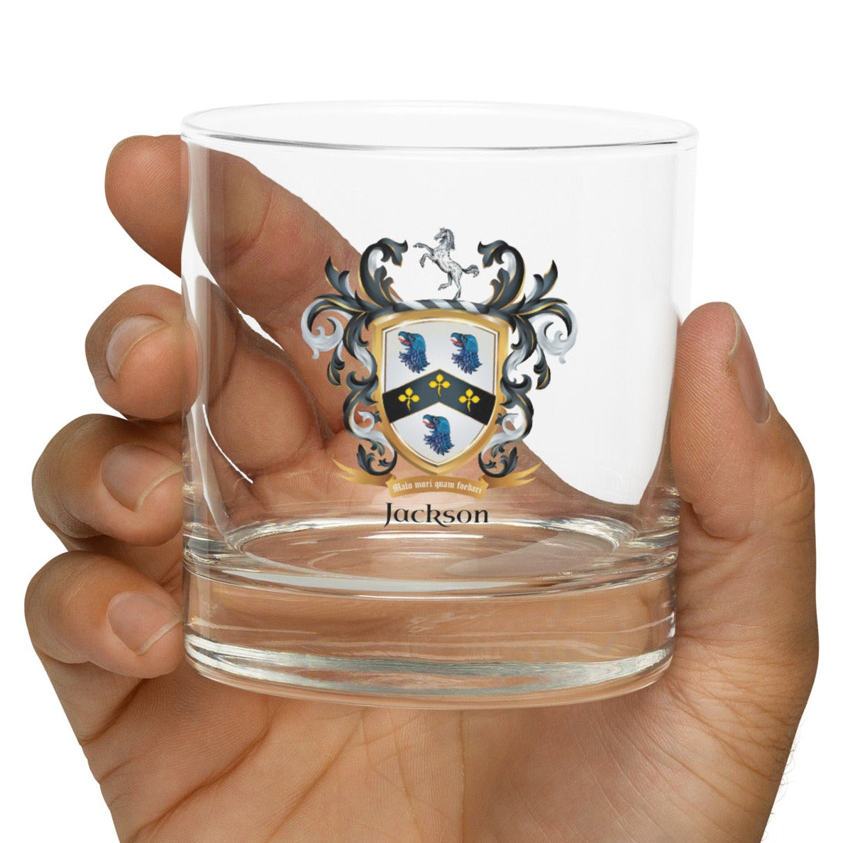 Hand holding a clear glass with a Jackson coat of arms design on a white background
