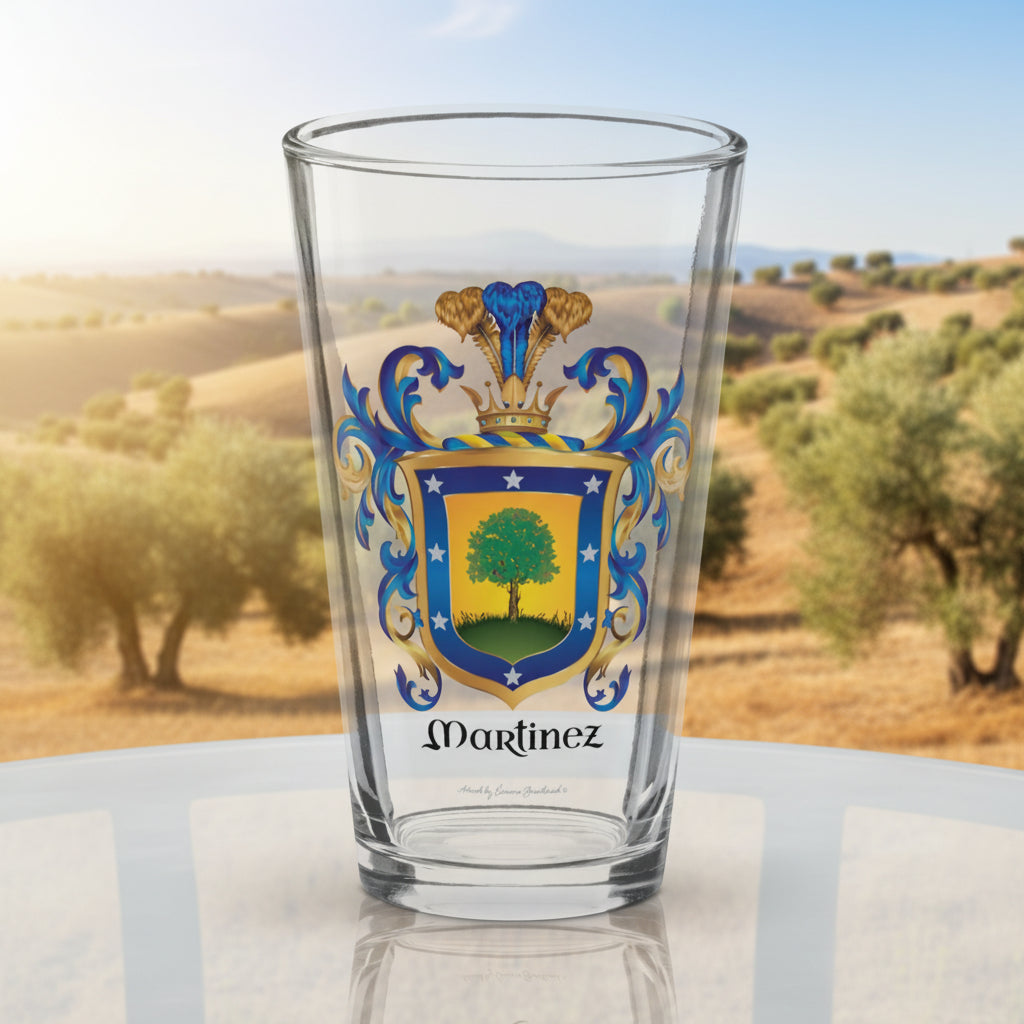 A pint glass on a glass table with the Martinez-Family-Crest on the front and trees in the background