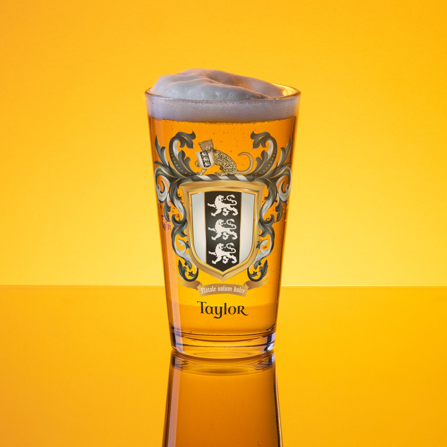 Beer glass with a Taylor family crest and the name 'Taylor' in black text below the shield that has 3 white lions on a black and white shield and 'Taylor' branding on a golden lit background