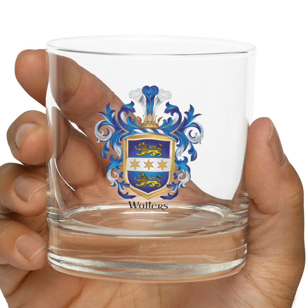 Clear glass with a Walters crest held in a hand against a white background