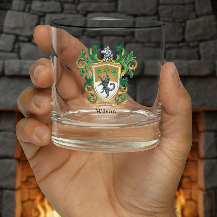 Clear glass with a Wilson family coat of arms design held by a hand with a fireplace in the background