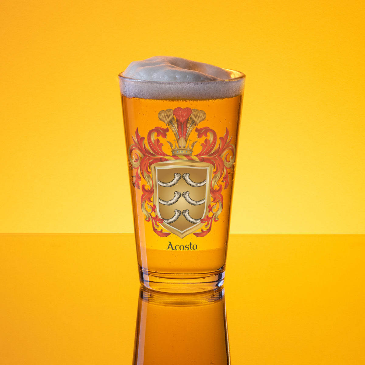 A clear pint glass filled with golden beer and topped with white foam, featuring a printed heraldic crest and the name 'Acosta' on a bright yellow gradient background.
