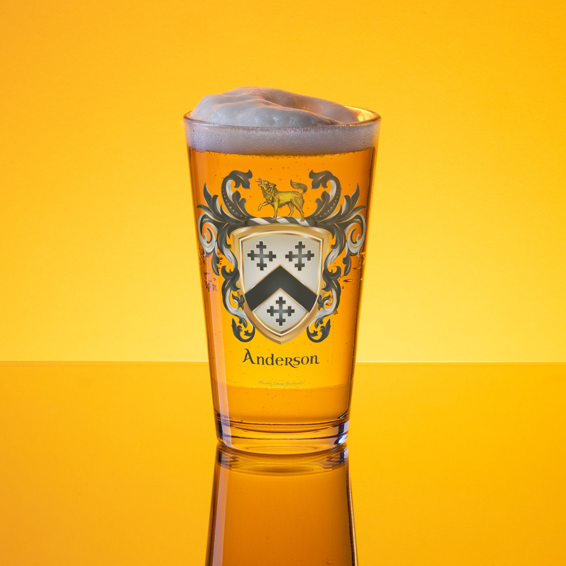 Beer glass with Anderson family crest on a gold lit background with beerin the pint glass which has an Anderson Family Crest featuring three black crosses and a black chevron on a white shield with a hound standing on thew crest of the shield