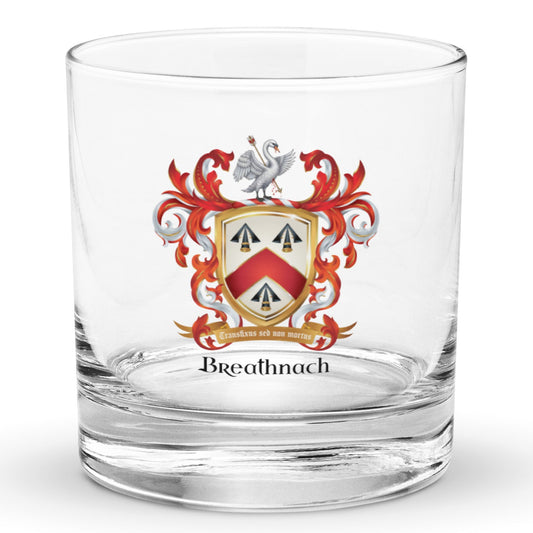A clear glass rocks tumbler with a custom family crest printed on the front, featuring a red, white, and gold coat of arms above the name 'Breathnach' in black text, shown on a white background.
