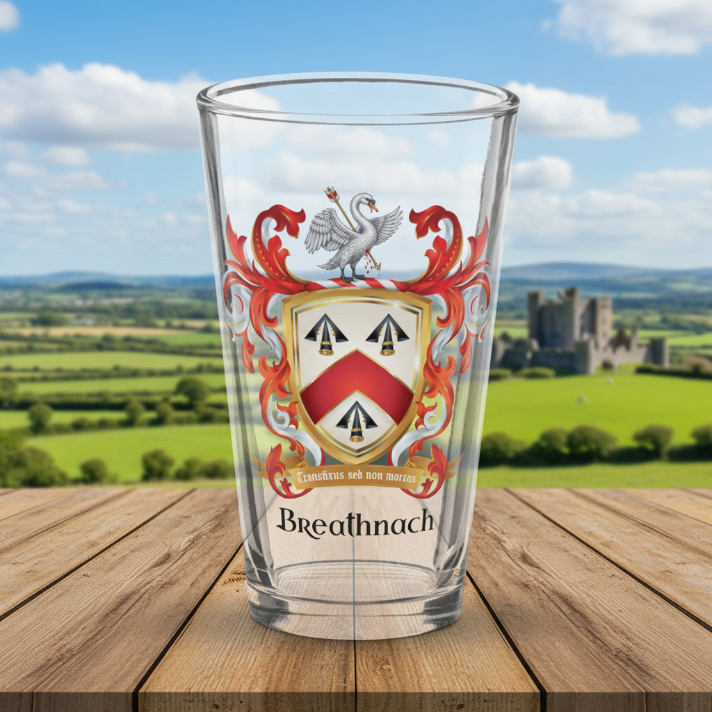 A clear pint glass featuring a printed Breathnach family crest on a wooden table with castle in background