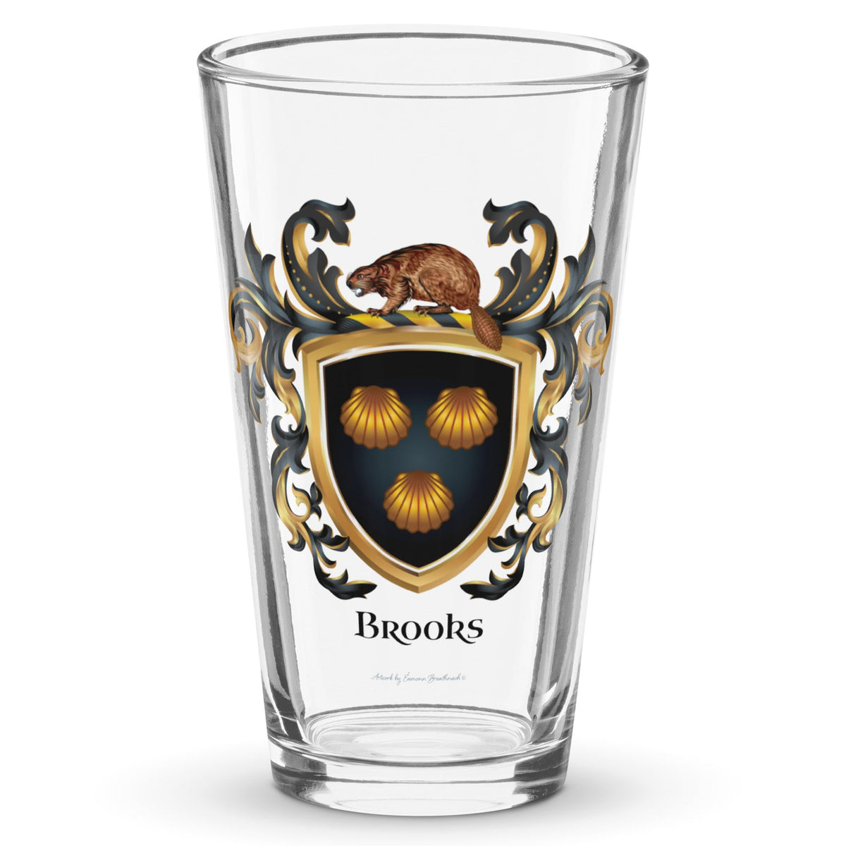 A clear classic pint beer glass on a white background, printed with the Brooks Family Crest featuring 3 clam shells on a black shield with a beaver on the crest of the shield.