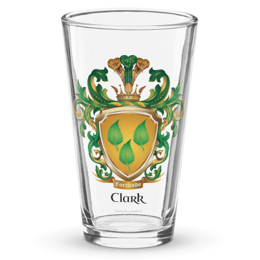 A classic clear pint beer glass on a white background with the Clark Family Crest on the front showing a golden shield with 3 green leaves.