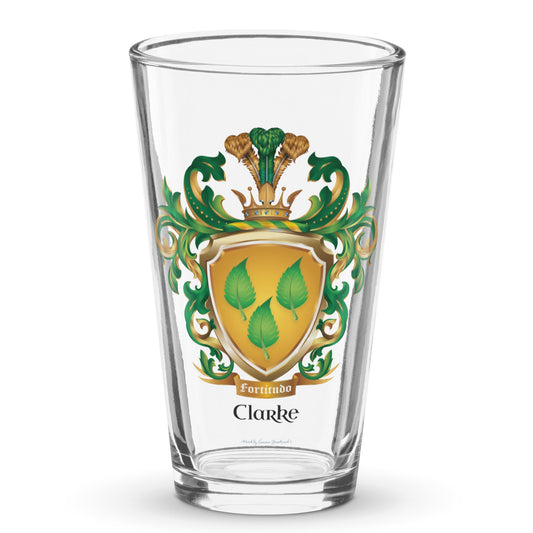 A pint beer glass on a white background with the Clarke Family Crest on the front showing a golden shield with 3 green leaves