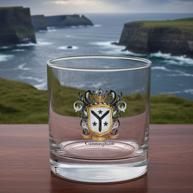 A clear glass rocks tumbler with a Cunningham family crest printed on the front, featuring a silver unicorn, black and silver mantling, and a gold shield with a black Y shape and 3 stars. The name 'Cunningham' is printed in black below the crest.