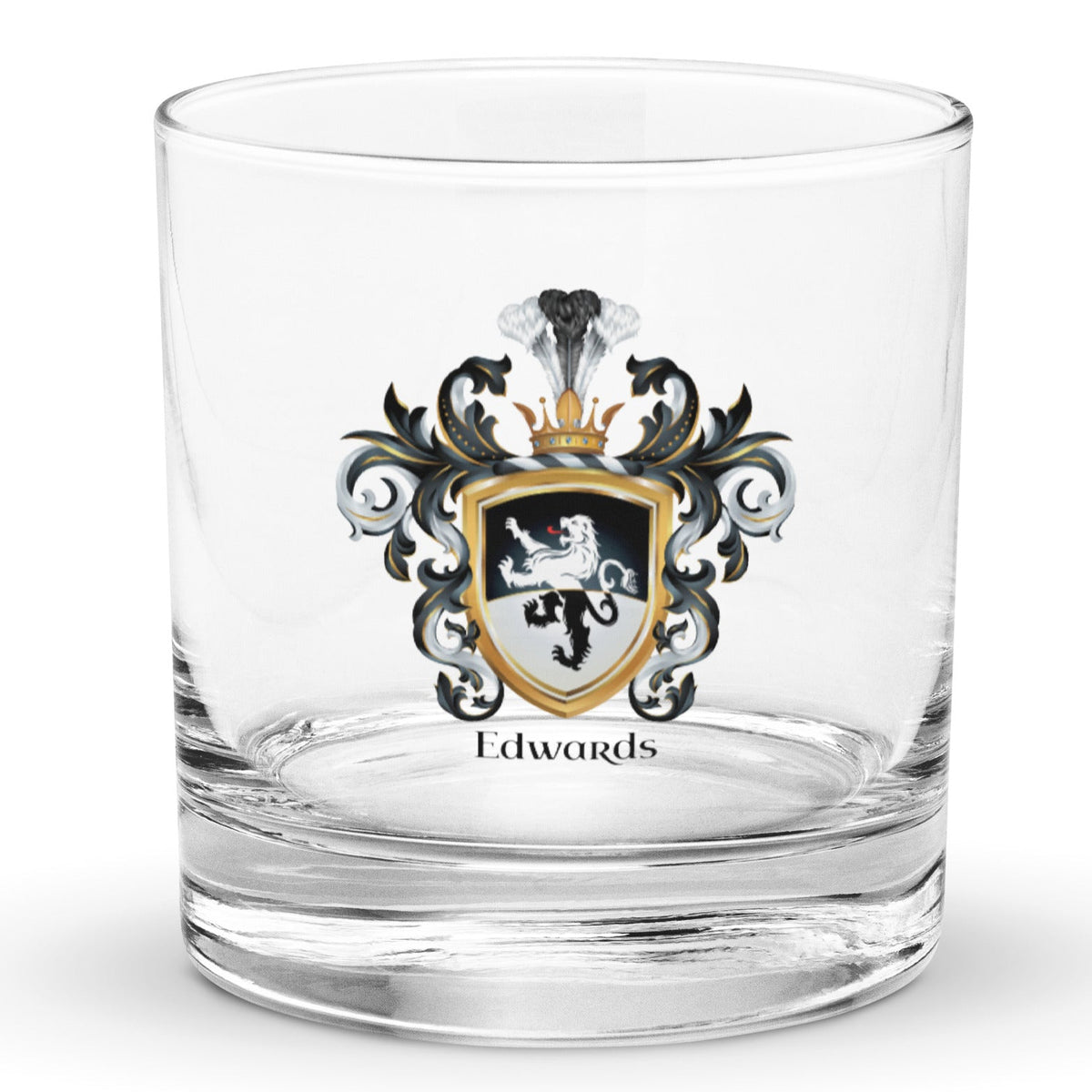 A clear classic heavy base rocks glass on a white background, printed with the Edwards Family Crest which features a lion on a horizontally split black and white shield