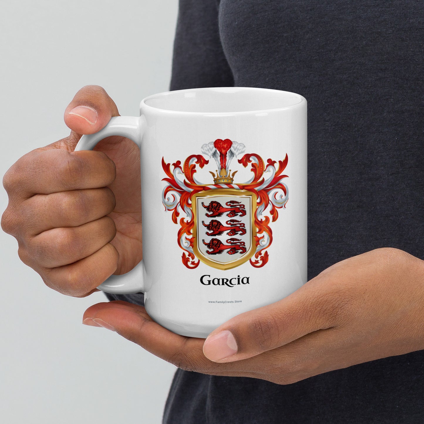 Person holding a white mug with a red, white and gold coat of arms  with 3 red lions and 'Garcia' text.