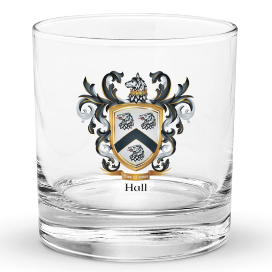 A clear classic heavy base rocks glass on a white background, printed with the Hall Family Crest. The crest features a white shield with a black chevron between three wolf heads (two above, one below), topped by wolf with a gold crown around it's neck and surrounded by detailed black and white mantling. The family name and motto appear beneath the shield.