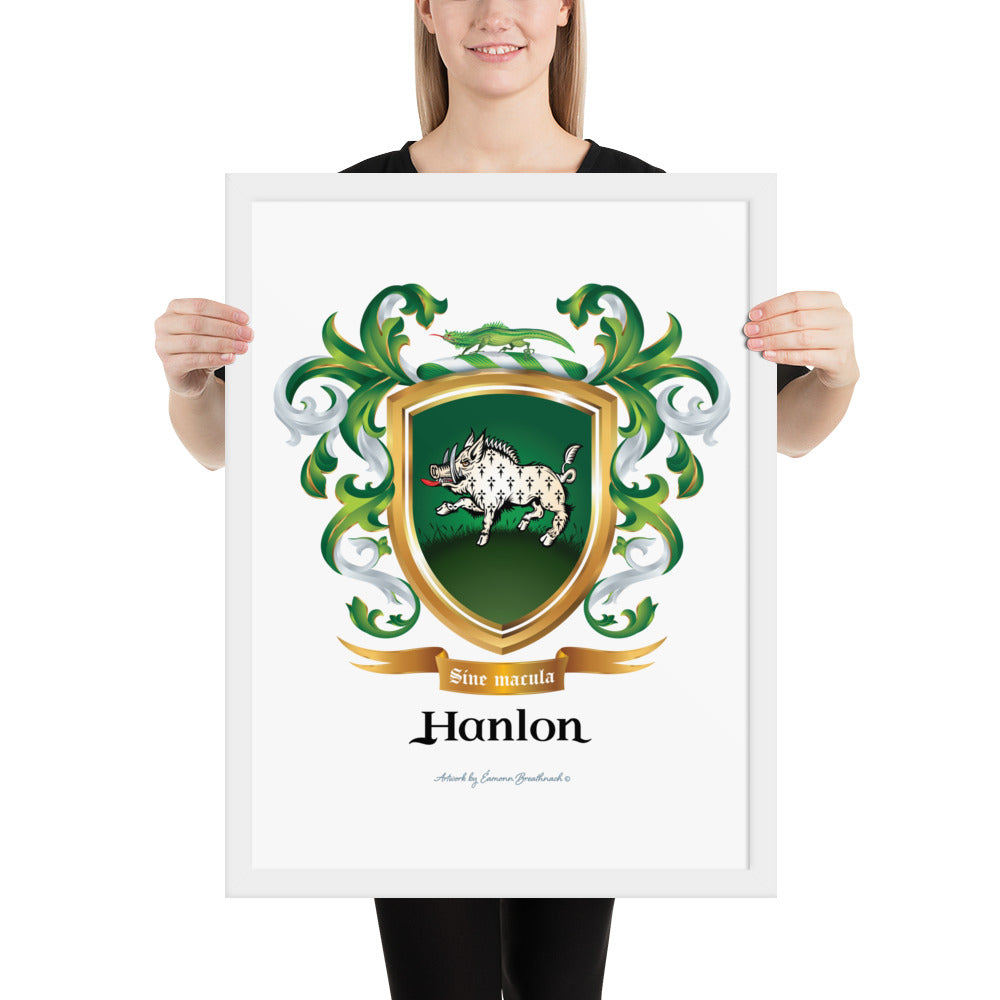 A woman sanding at a white background holding a framed print of the Hanlon Family Crest featuring a white boar with ermine pattern on a green shield. The frame is white and the coat of arms itself is printed on a white background.