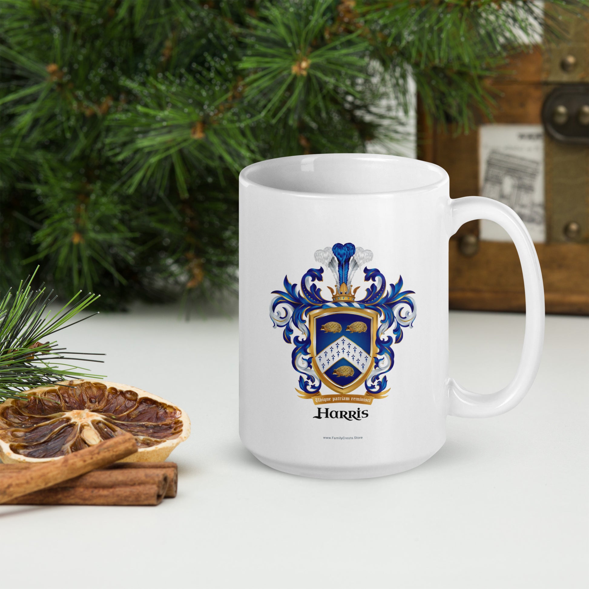 White mug with a coat of arms design and 'Harris' text, placed on a surface with decorative Christmas elements.