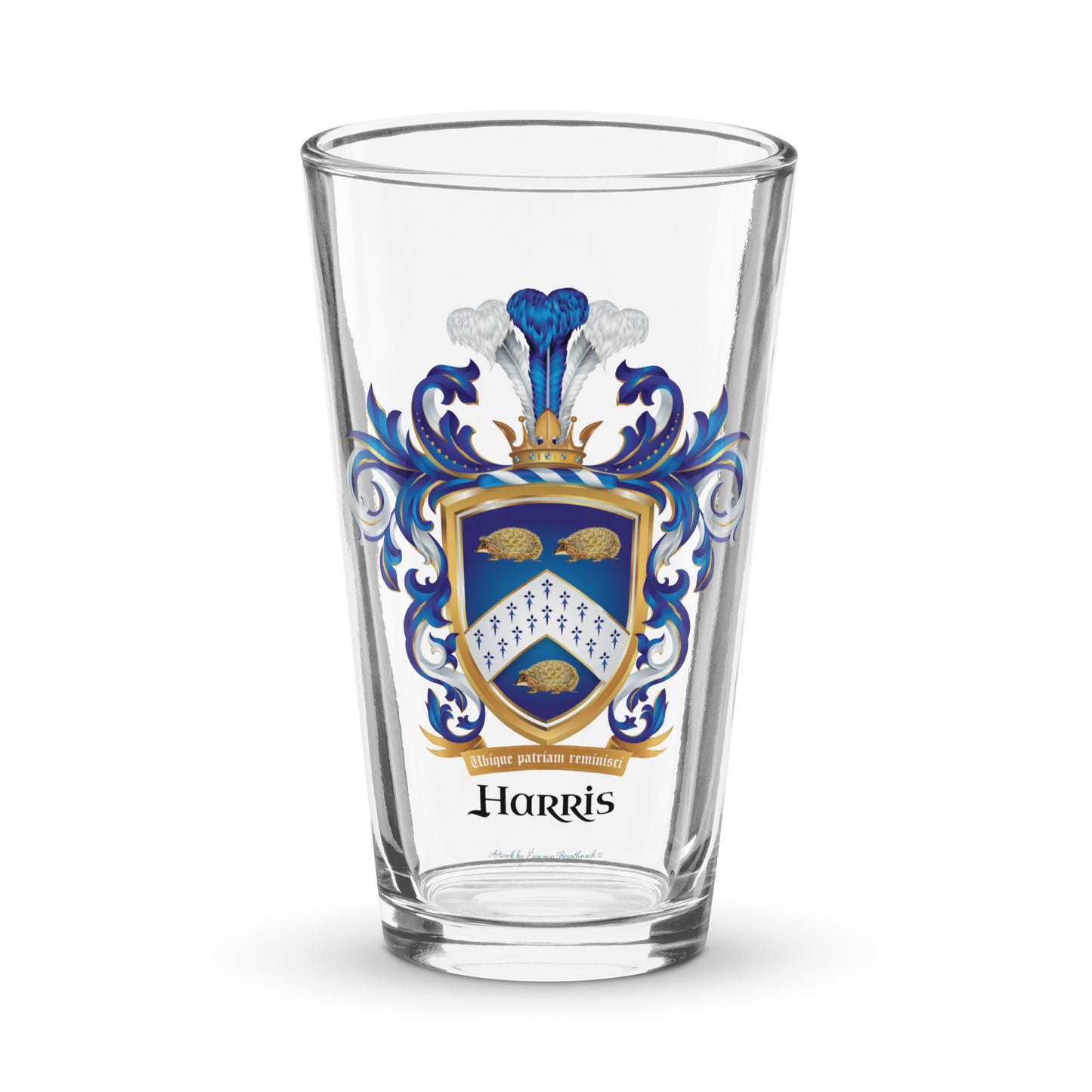 A clear pint beer glass with the Harris Family Crest on the front featuring 3 hedgehogs on a blue shield with a white chevron containing an ermine pattern pictured against a white background.