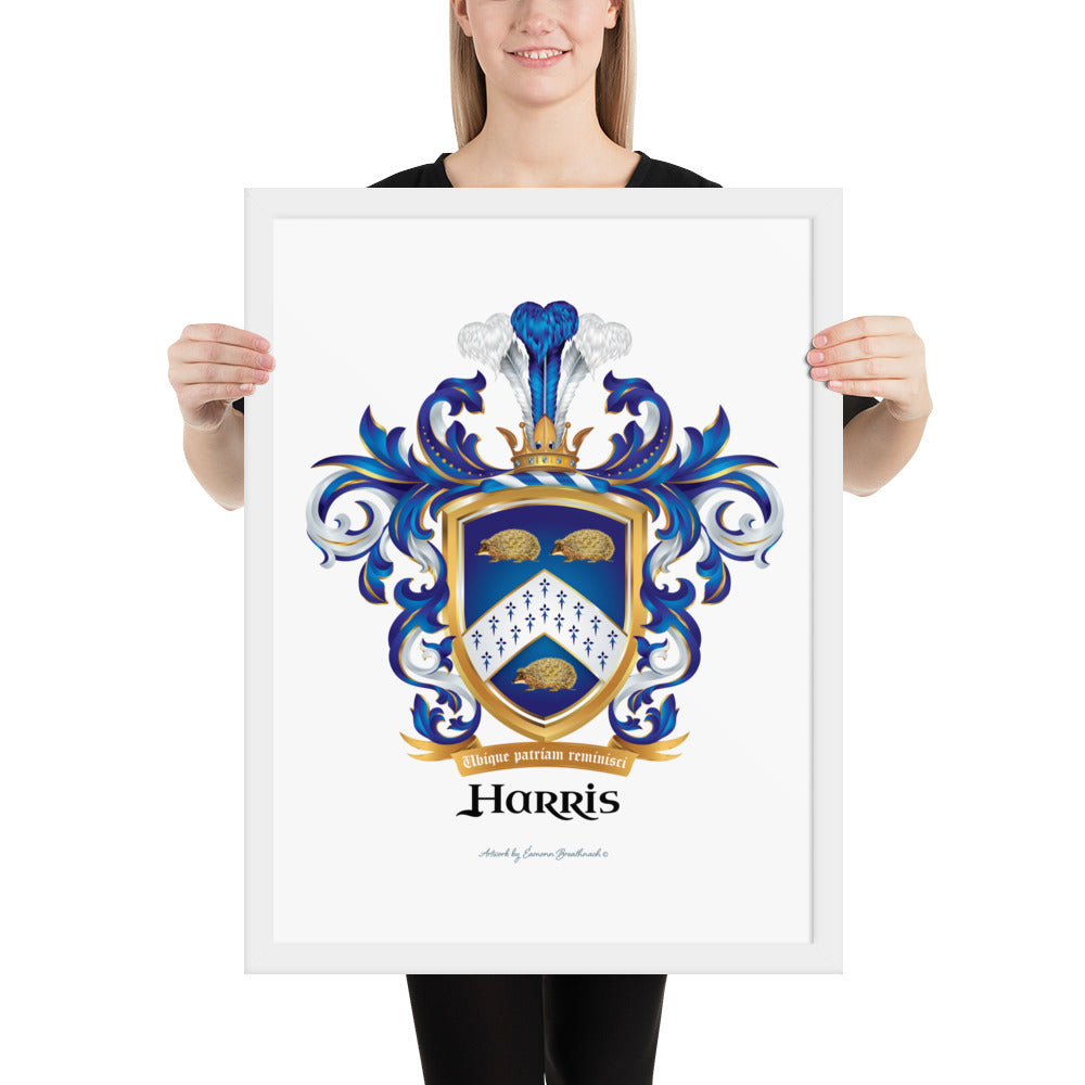 A woman standing up holding a white framed print of the Harris Family Crest featuring 3 hedgehogs.