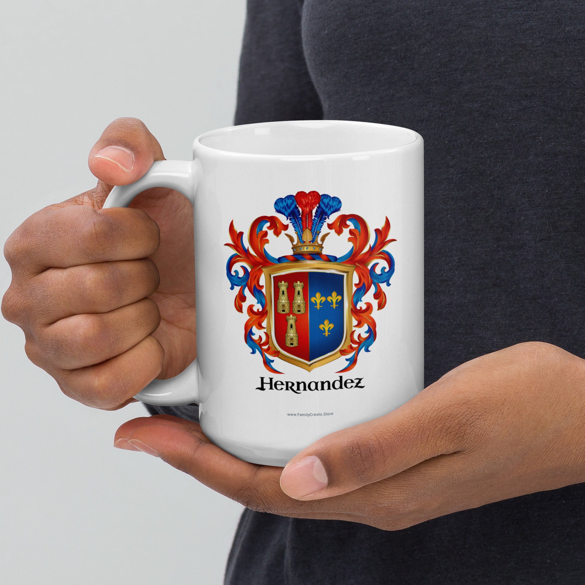 Person holding a white mug with a red, blue and gold family crest and 'Hernandez' text on a light gray background
