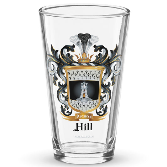 A classic clear pint beer glass standing in white space with the Hill Family Crest which features a white tower with 3 small towers on top of it on a black and white shield with ermine patterns, printed on it.