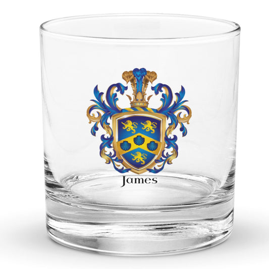 A clear classic heavy base rocks glass on a white background, printed with the James Family Crest which features a blue shield with a golden chevron containing 3 blue clam shells and two gold lions above the chevron and one beneath it.