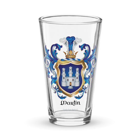 A clear pint glass featuring a personalized family crest with the name 'Martin' printed below. The crest includes a blue and gold shield with a white castle, flanked by blue mantling,
