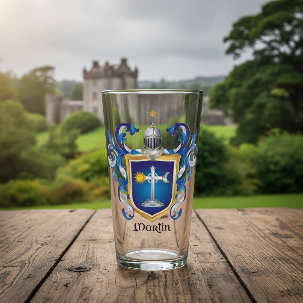 A clear pint glass featuring a printed Irish Martin family crest with a blue shield, silver and gold details, and the name 'Martin' printed below, shown on wooden table with Ballinahinch Castle in the background.