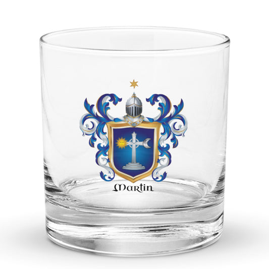 A clear glass rocks tumbler with an Irish Martin family crest printed on the front. The crest features a blue and gold shield with a white cross, blue scrollwork, and a small gold star above a helmet, with the name 'Martin' printed in black below the crest.