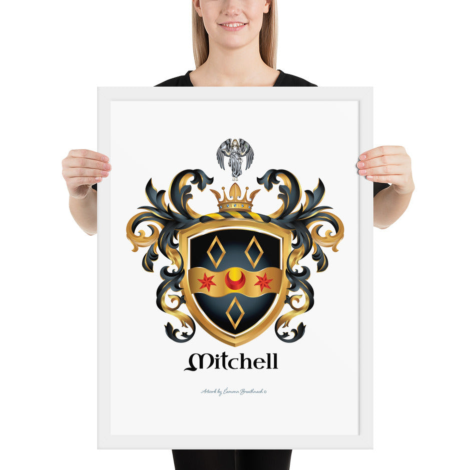 A woman standing in a white background, holding a white framed print of the Mitchell Family Crest featuring a black shield witha wavy gold ribbon with 2 red stars and a red cresent and 3 gold diamonds and an angel holding a dove above the shield on the crest.