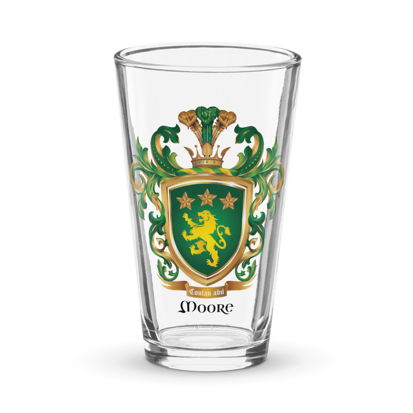 Clear pint beer glass featuring The Moore Family Crest showing a green shield with a gold lion and three gold stars above the lion with the motto and Moore name beloe the shield and a crown above and green and gold mantling all around  on a white background