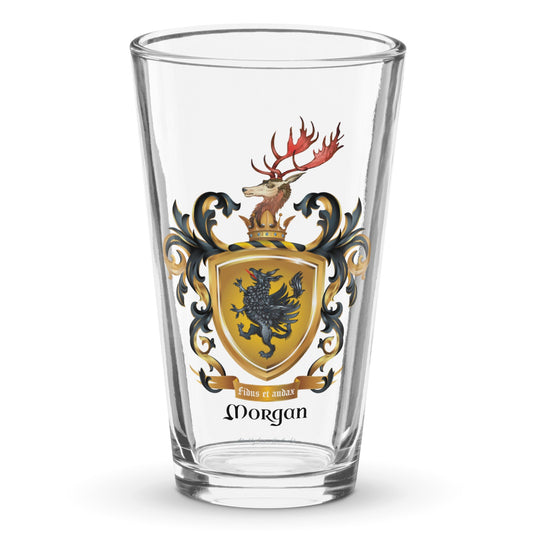 A clear classic pint beer glass on a white background, printed with the Morgan Family Coat of Arms featuring a black griffin on a gold shield with a stag on the crest.