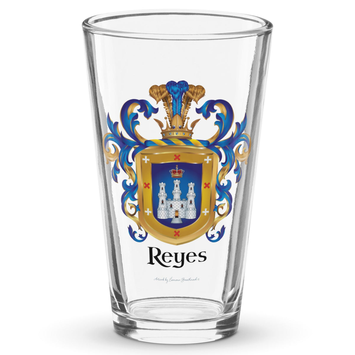 A clear classic pint beer glass on a white background, printed with theReyes Family Crest which features a blue shield with a white castle and crown.