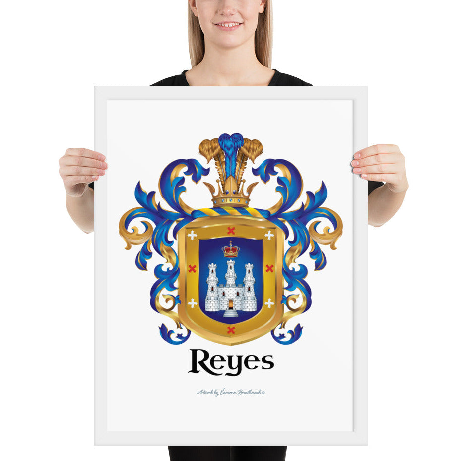 A woman standing in a white background, holding a white framed print of the Reyes Family Crest which features a blue shield with a white castle and crown.