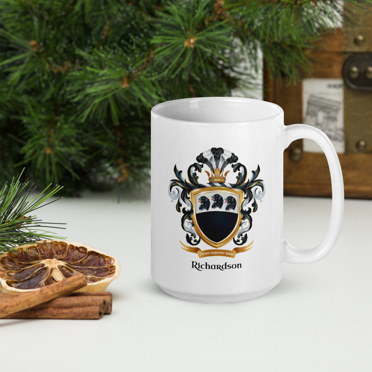 A white ceramic mug with a black, white, and gold Richardson family crest and the name 'Richardson' printed below it. The mug is styled on a white surface with a dried orange slice, cinnamon sticks, and green pine branches in the background.