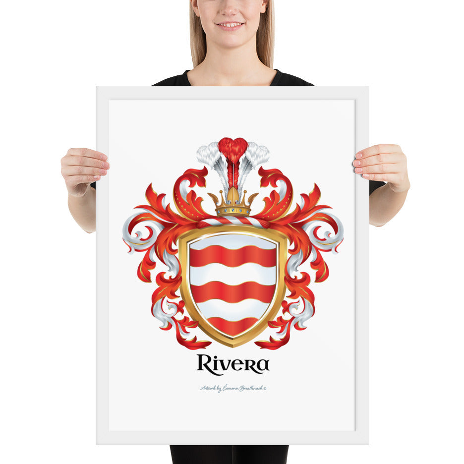 A woman standing in a white background, holding a white framed print of the Rivera Family Crest featuring 3 wavy red bands on a white shield