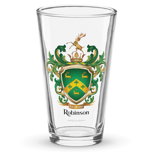 A clear pint glass with the Robinson-Family-Crest print on the front of the glass featuring a green shield with three gold stags, a golden chevron with 3 shamrocks and above the shield a stag standing on a gold crown and below the shield a motto and the name Robinson in black letters.