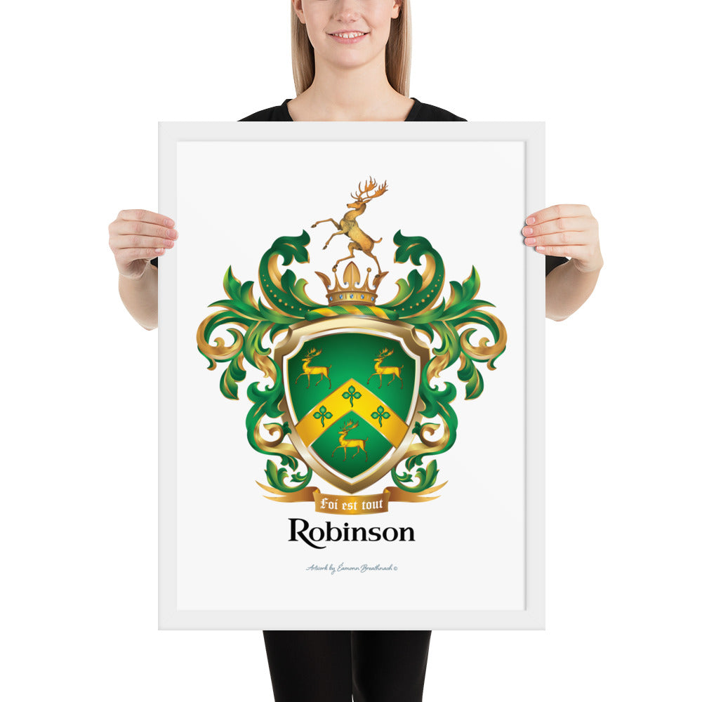A framed print of the Robinson-Family-Crest on white paper featuring a green shield with three gold stags, a golden chevron with 3 shamrocks and above the shield a stag standing on a gold crown and below the shield a motto and the name Robinson in black letters.