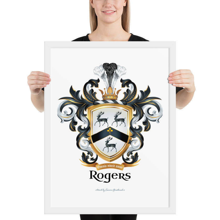 A woman standing in a white background, holding a white framed print of the Rodgers Family Crest which features 3 black stags and a black chevron on a white shield.