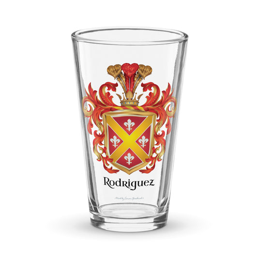 A pint beer glass with the Rodriguez Family Crest on the front featuring white fleur de lys with gold edges and a diagonal gold cross on a red shield of the coat of arms