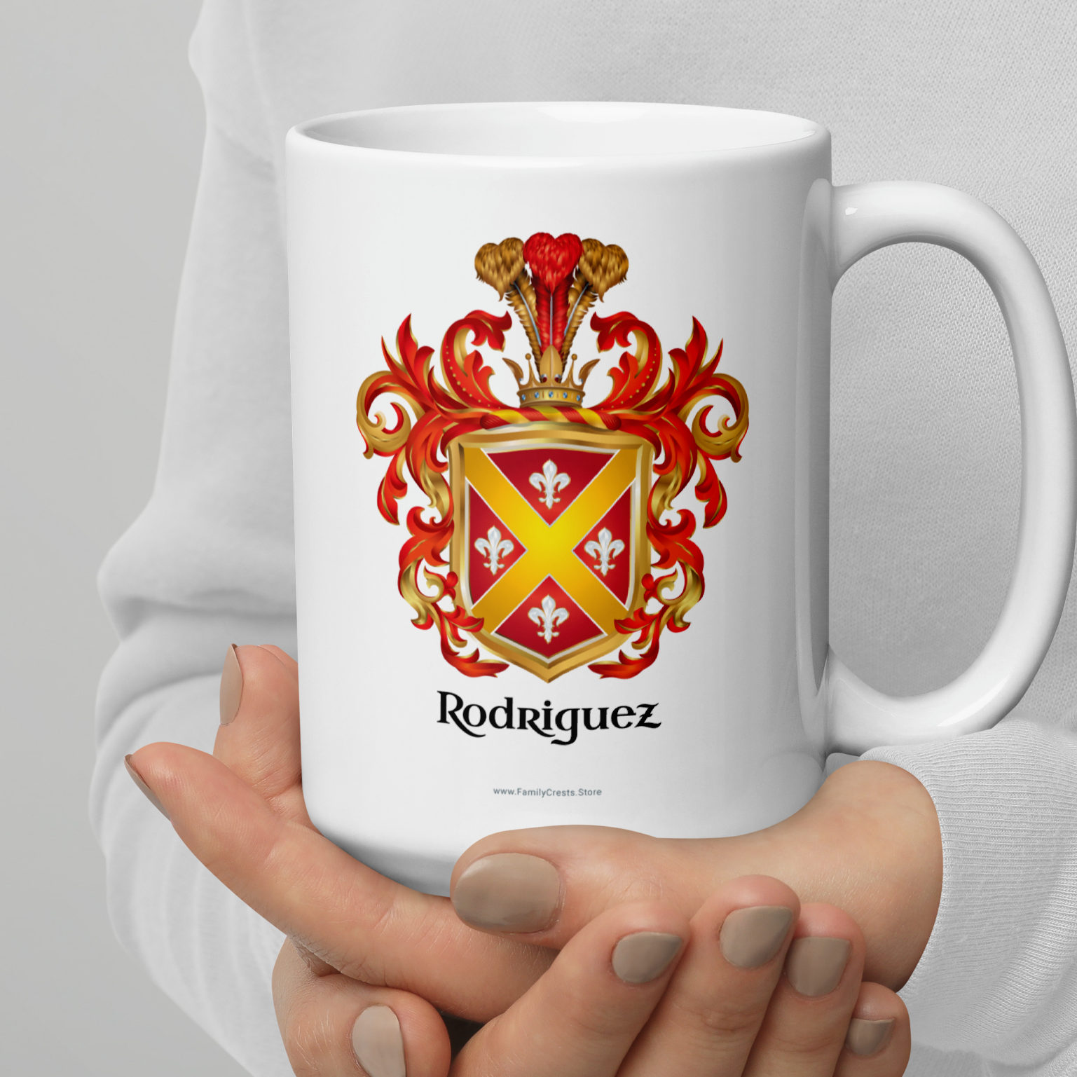 White mug held by a person with Rodriguez Family Crests with a gold cross and fleur-de-lys on a red shield and under the coat of arms the name 'Rodriguez' in black text.