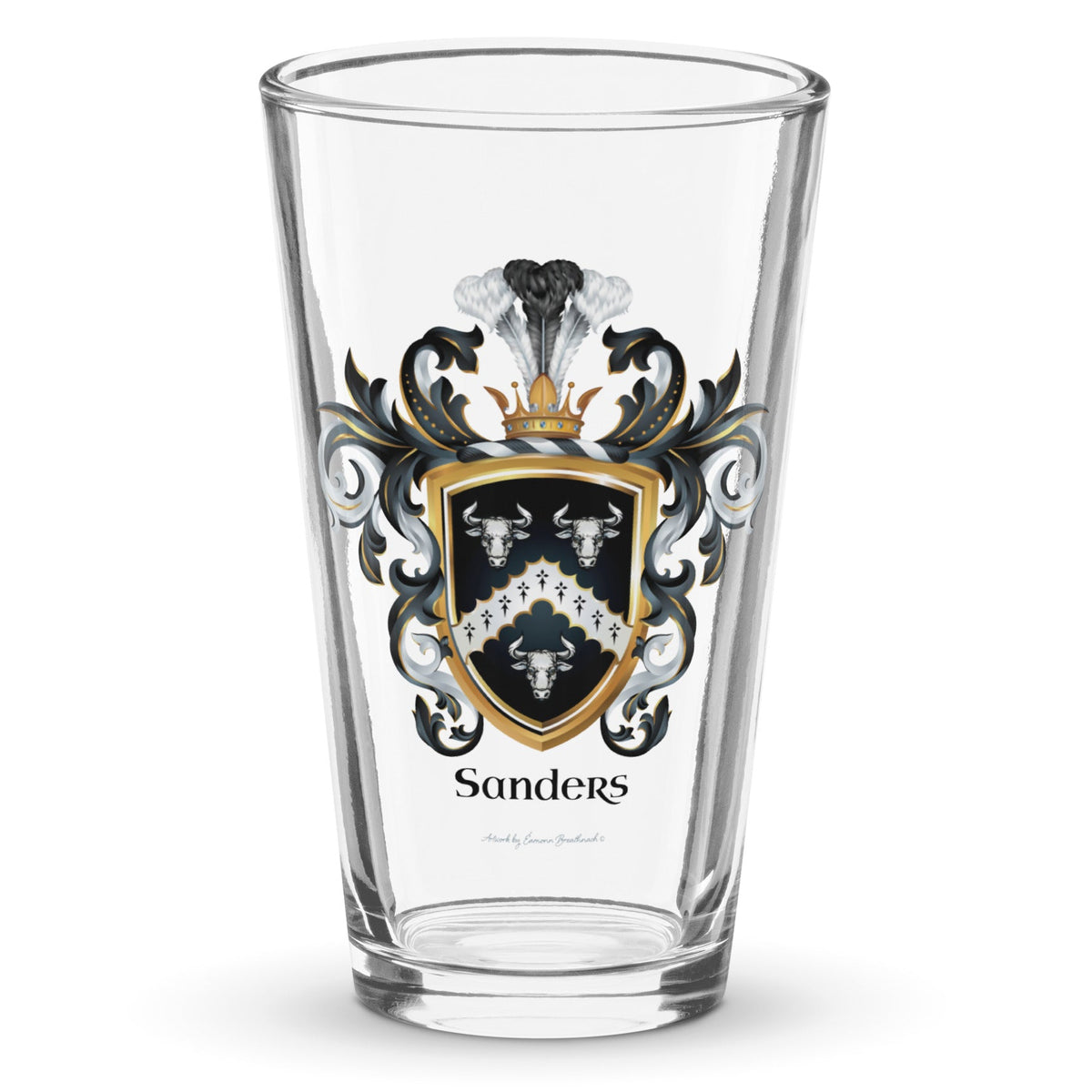 A clear classic pint beer glass on a white background, printed with the Sanders Family Crest featuring 3 white bull heads and a chevron on a black shield.