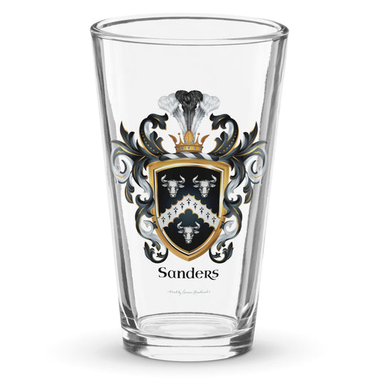 A clear classic pint beer glass on a white background, printed with the Sanders Family Crest featuring 3 white bull heads and a chevron on a black shield.