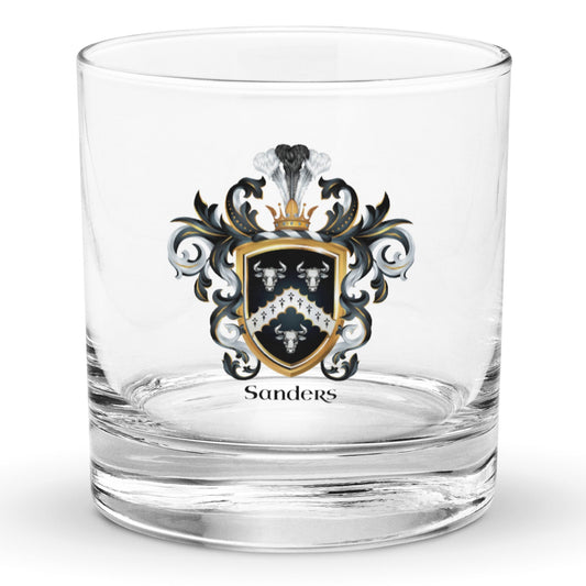 A clear classic heavy base rocks glass on a white background, printed with the Sanders Family Crest featuring 3 white bull heads and a chevron on a black shield.