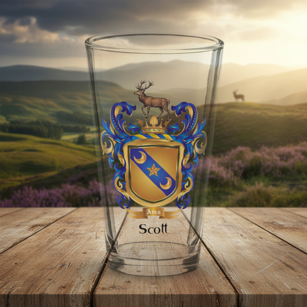 A clear pint glass featuring the Scott Family Crest on a wooden table top with a highland scene in the  background.