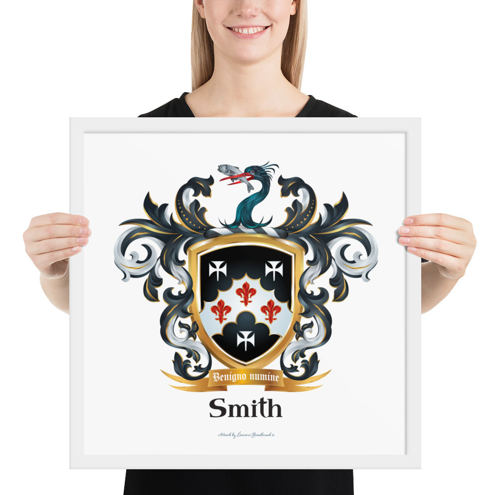 A woman standing in a white background holding a framed print of a Smith Family Crest that features a black shield with three white stylised crosses and theree red fleur-de-lys and also has a heron's head holding a fish in its beak on the crest above the shield.