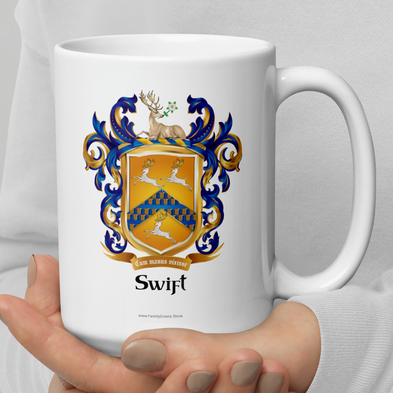White mug with a Swift Family Crest coat of arms featuring three running white stags held by a person against a light gray background