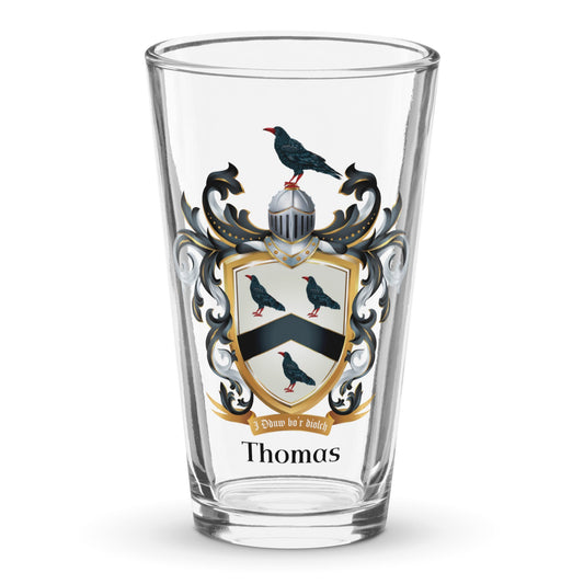 Clear classic pint beer glass with a Thomas Family Crest  featuring 3 black crows and a chevron, on a white background.