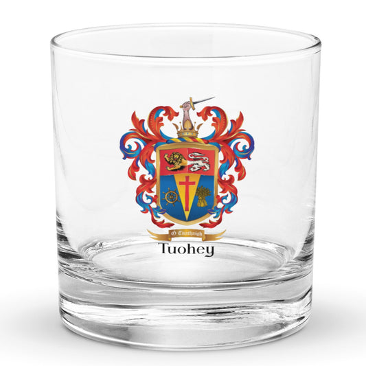 A classic rocks glass on a white background ith a Tuohey_Family_Crest_on the front of the glass featring a lion and a cross.