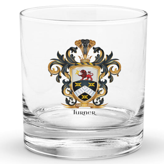 A clear classic heavy base rocks glass on a white background, printed with the Turner Family Crest