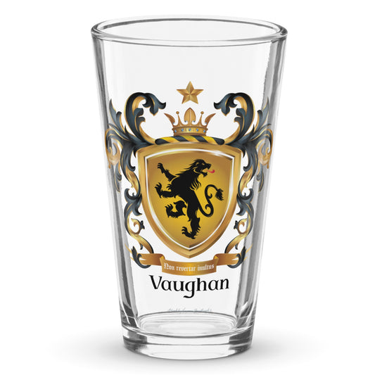 A clear classic pint beer glass on a white background, printed with the Vaughan Family Crest which has a gold shield with a black standing lion looking back.
