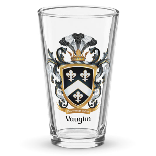 A clear classic pint beer glass on a white background, printed with the Vaughn Family Crest featuring a shield with 3 fleur de lis and a chevron.